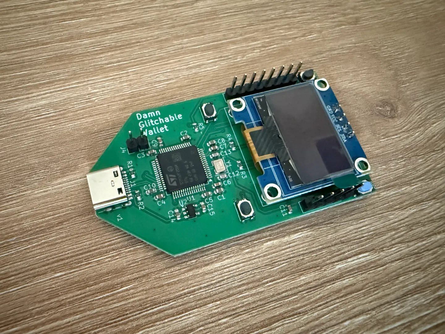 Green Damn Glitchable Wallet board with a display, buttons, USB connector, and pin headers